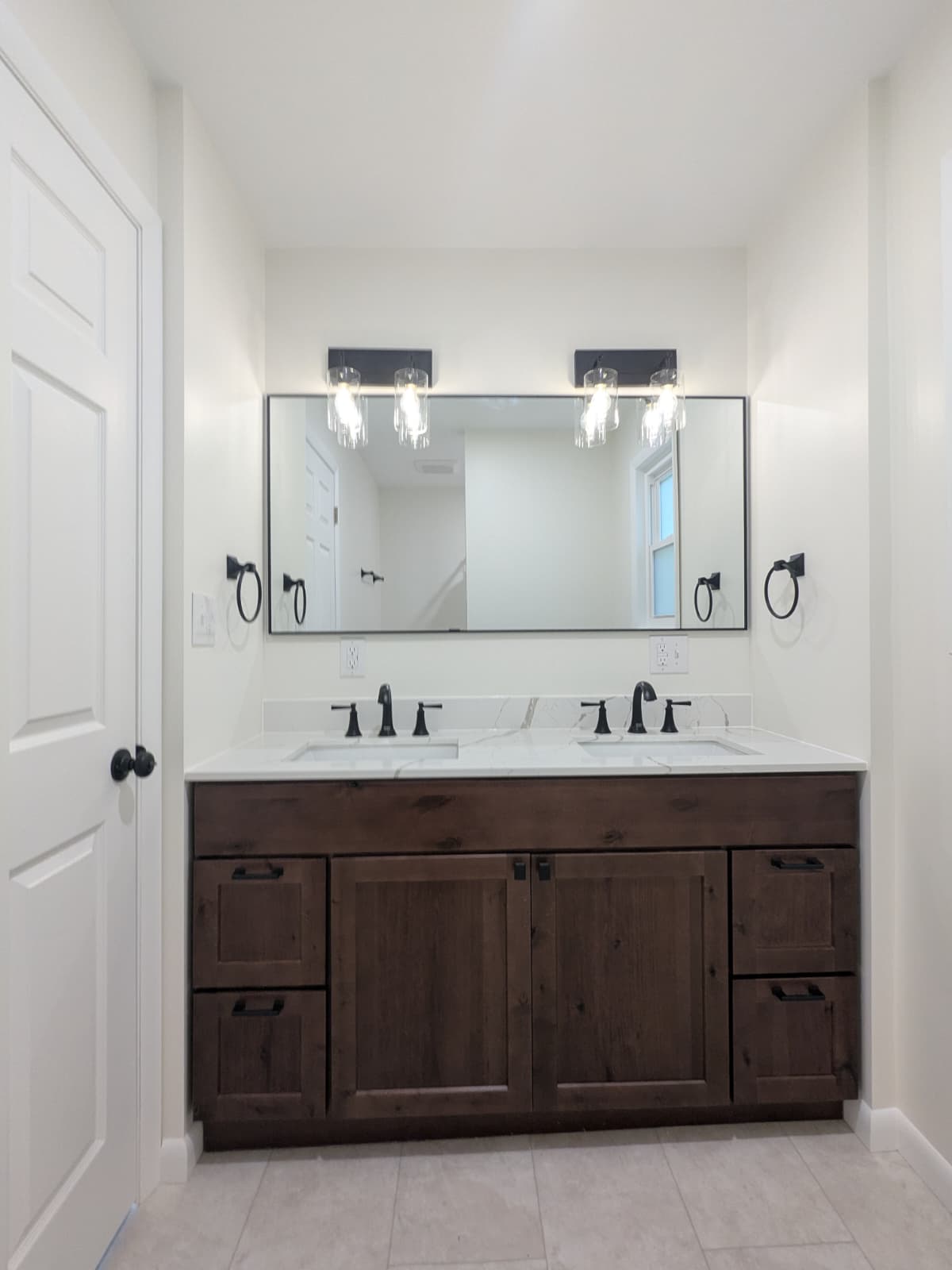 Double bathroom vanity with dark wood cabinets, quartz countertop, and matte black fixtures