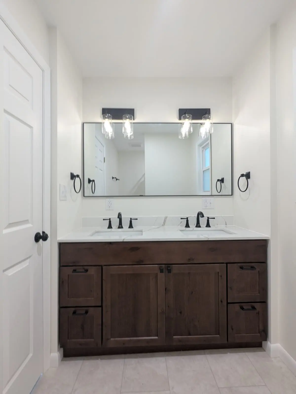 Double bathroom vanity with dark wood cabinets, quartz countertop, and matte black fixtures