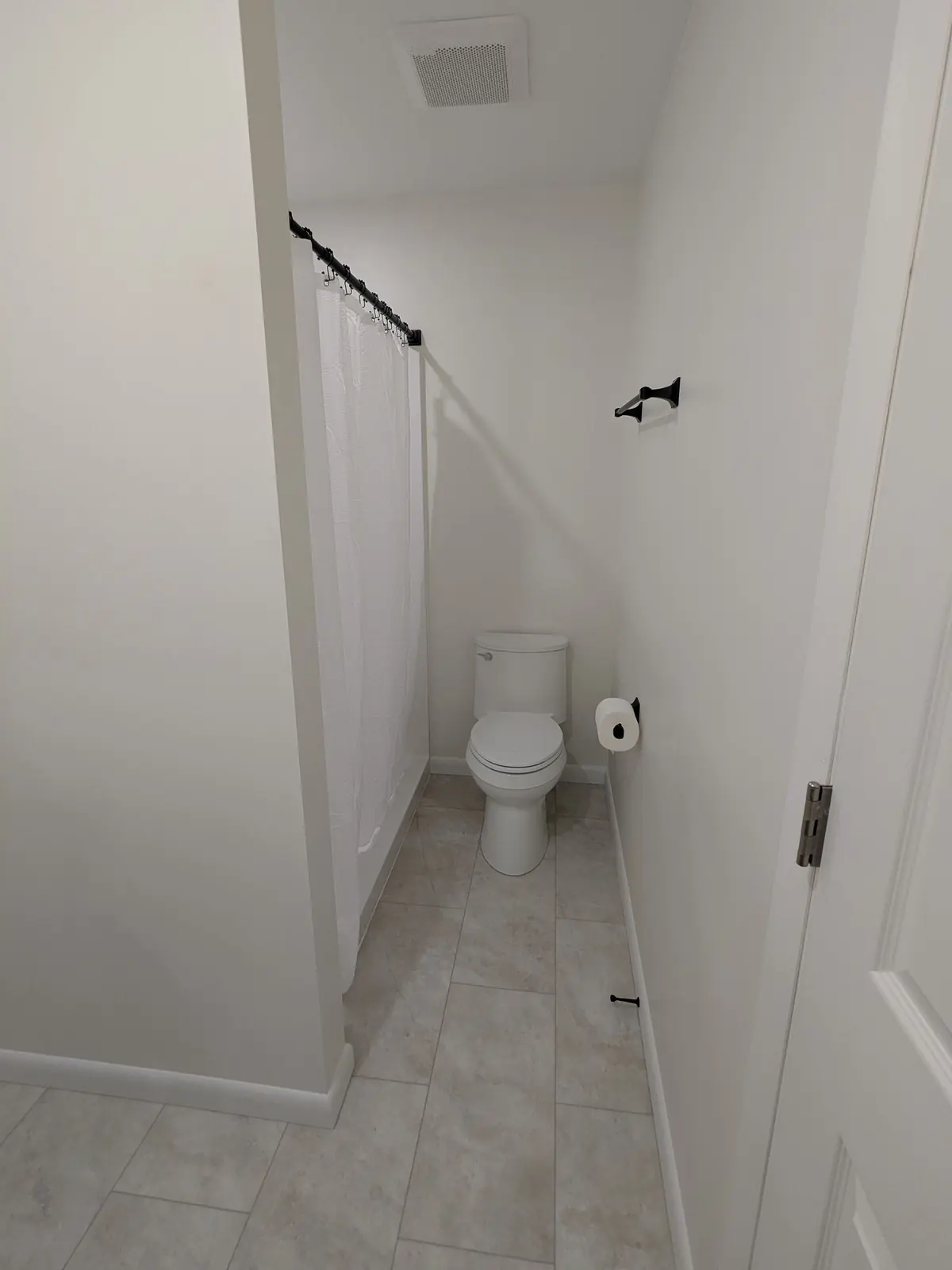 Bathroom remodel with a new fiberglass shower, toilet, and matte black hardware